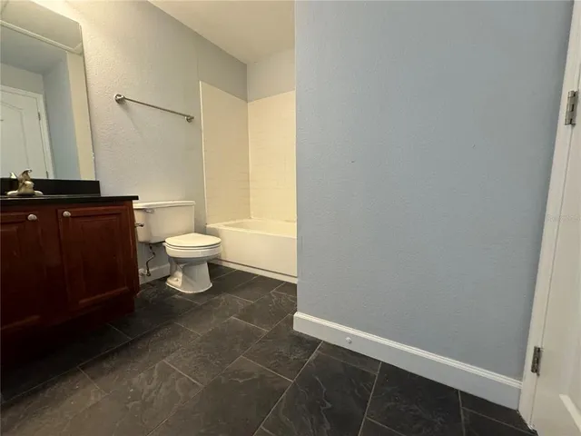 a bathroom with a granite countertop toilet a sink and a bathtub