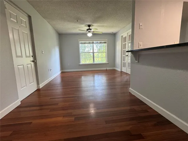 a view of an empty room with wooden floor and a window