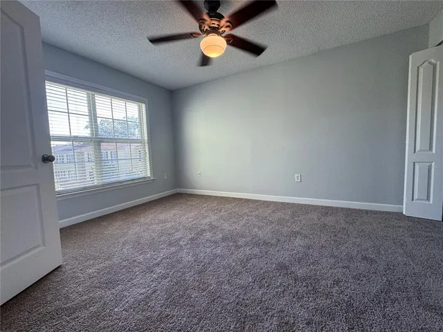 an empty room with windows and fan