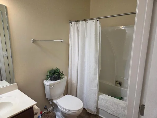 a bathroom with a toilet a shower curtain and a sink