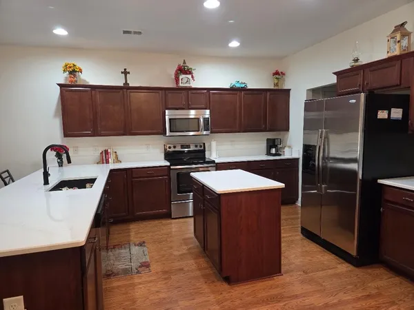 a kitchen with kitchen island a sink wooden cabinets and stainless steel appliances