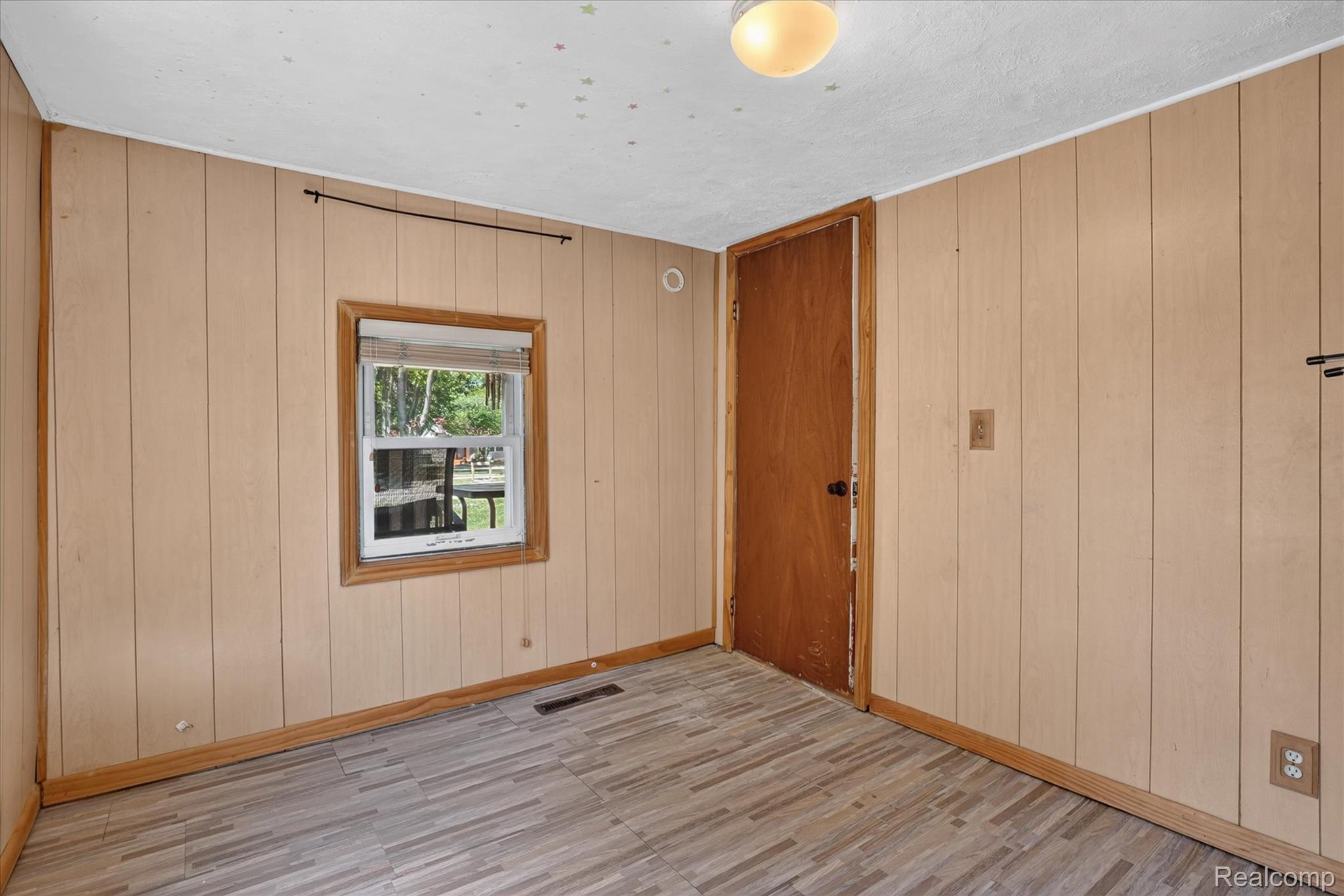 508 Deland Road Flushing, MI 48433 - Photo 23 of 38 Room featuring paneled walls, wood-finish flooring, a single window with blinds, and a flush-mount ceiling light