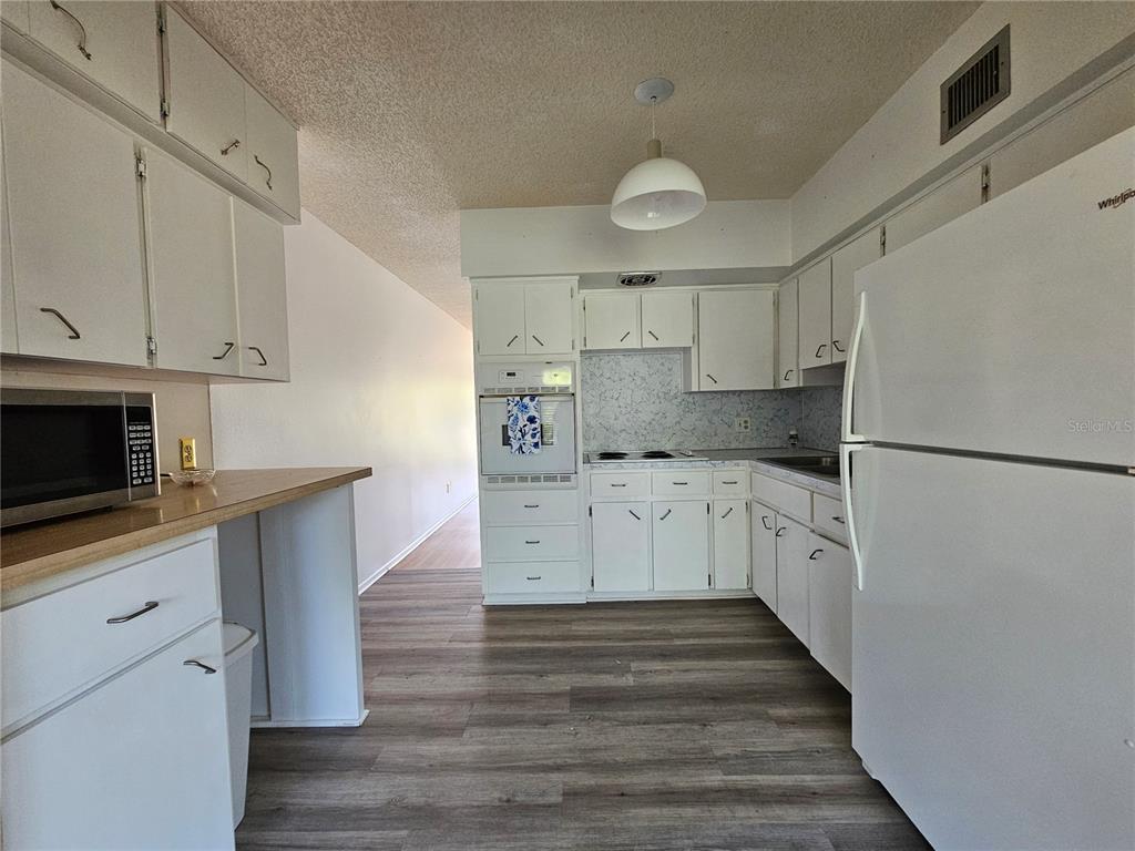 2386 Sumatran Way, Unit 44 Clearwater, FL 33763 - Photo 4 of 67 a kitchen with white cabinets stainless steel appliances and wooden floor