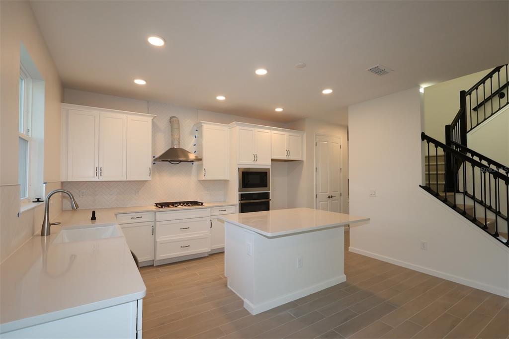 5426 Park Guell Street St. Cloud, FL 34771 - Photo 5 of 64 a large kitchen with stainless steel appliances a large counter top a stove and a sink