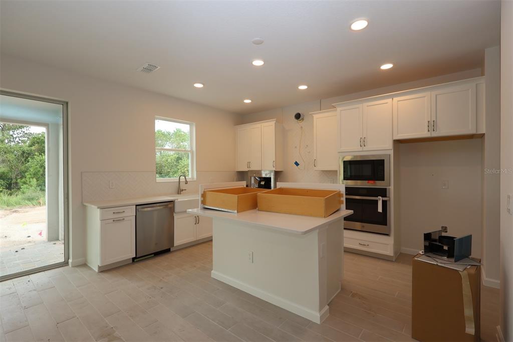5426 Park Guell Street St. Cloud, FL 34771 - Photo 6 of 64 a large kitchen with kitchen island a sink stainless steel appliances and cabinets