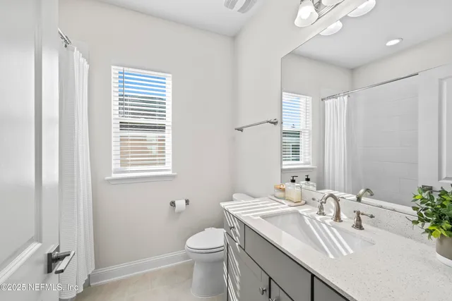 a bathroom with a granite countertop sink toilet and mirror