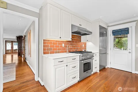 a kitchen with white cabinets and wooden floor