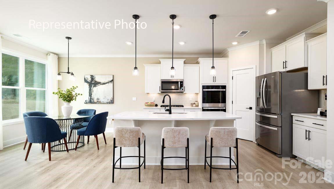 3117 Spring Iris Drive Denver, NC 28037 - Photo 36 of 42 a kitchen with stainless steel appliances kitchen island granite countertop a table chairs and a sink