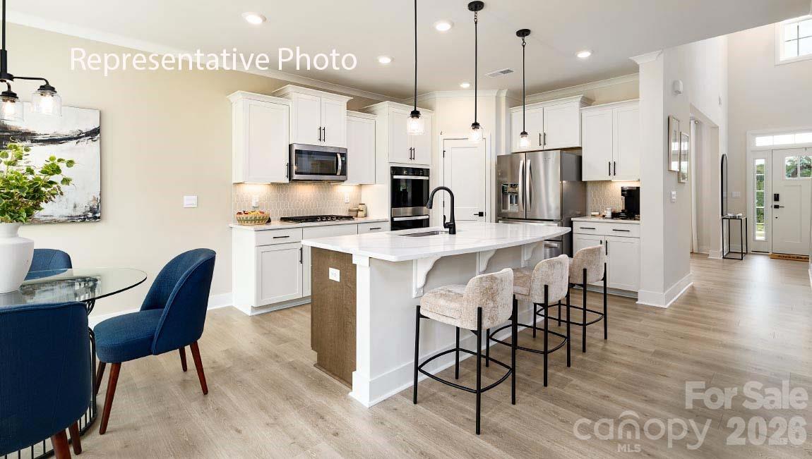 3117 Spring Iris Drive Denver, NC 28037 - Photo 37 of 42 a kitchen with stainless steel appliances a dining table chairs stove and refrigerator