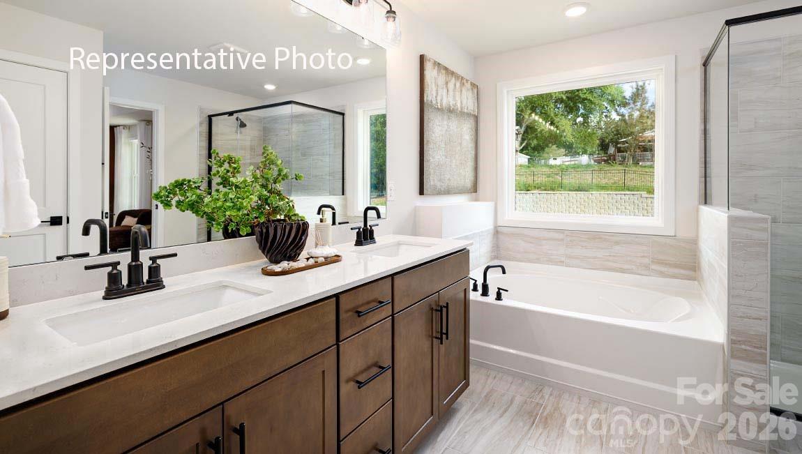 3117 Spring Iris Drive Denver, NC 28037 - Photo 7 of 42 a bathroom with a double vanity sink a large mirror a bathtub and next to a window