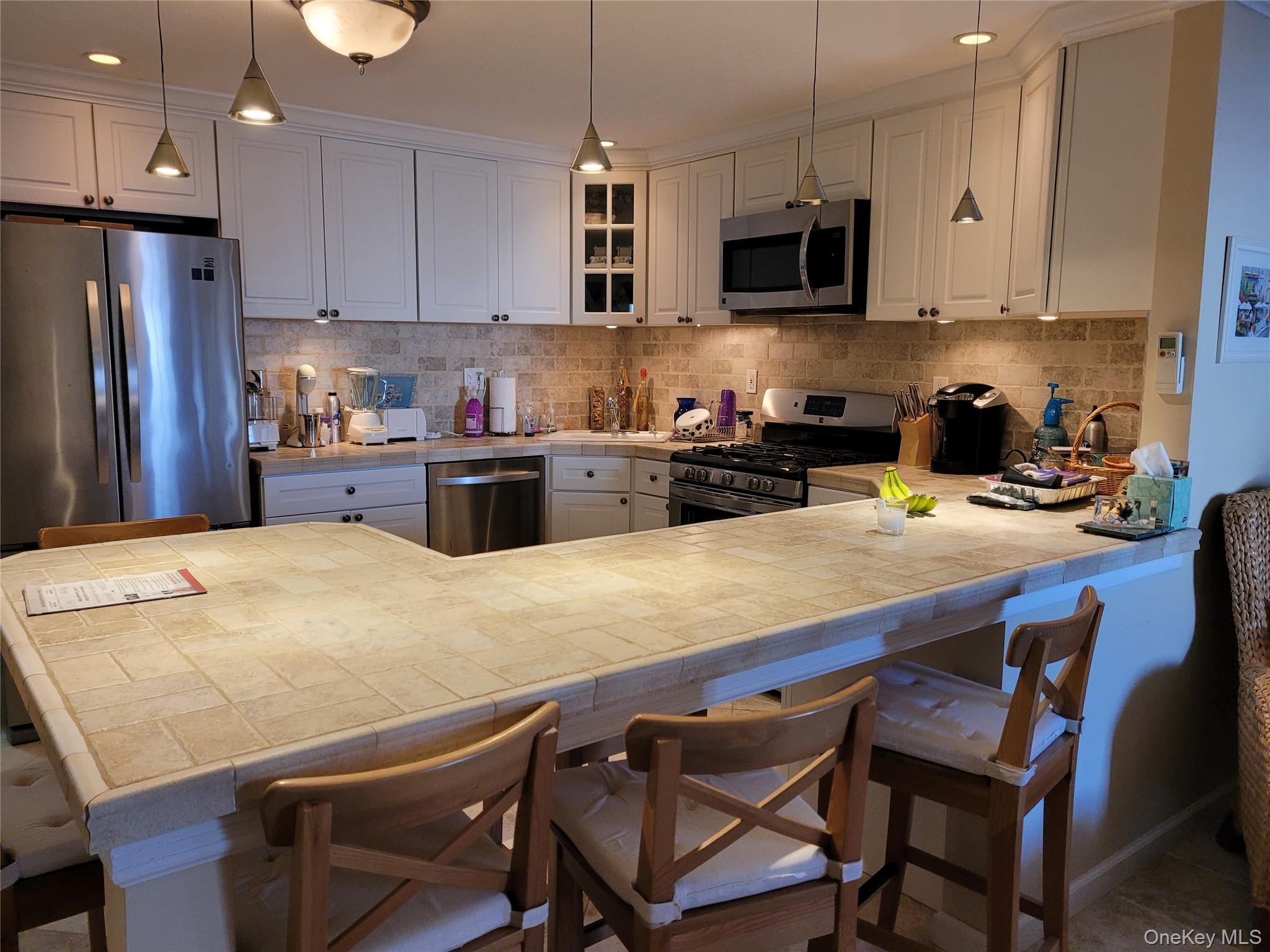 79 Rochester Avenue, Unit GARDEN Long Beach, NY 11561 - Photo 5 of 15 a kitchen with a table chairs microwave and refrigerator
