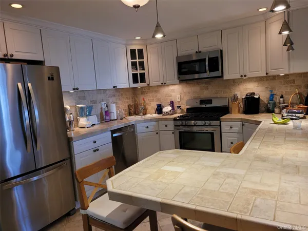 a kitchen with stainless steel appliances granite countertop a refrigerator sink stove microwave and cabinets