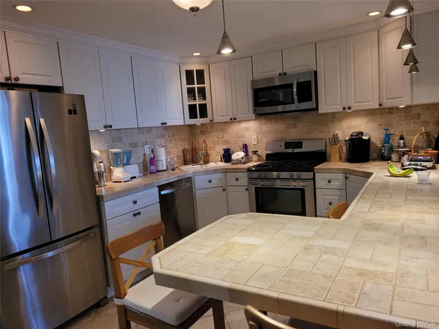 a kitchen with stainless steel appliances granite countertop a refrigerator sink stove microwave and cabinets