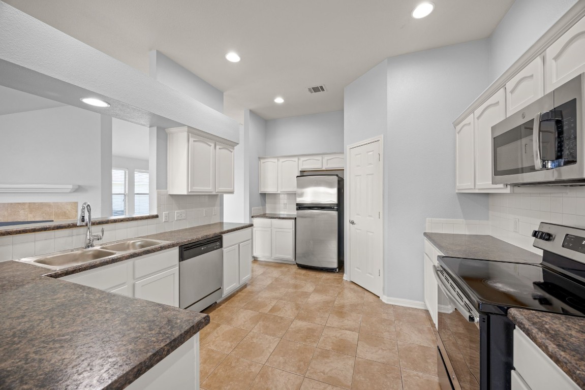 1323 Anna Palm Way Round Rock, TX 78665 - Photo 12 of 29 a kitchen with stainless steel appliances granite countertop a sink stove and refrigerator