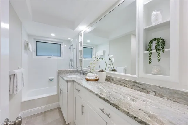 a bathroom with a granite countertop sink mirror and bathtub