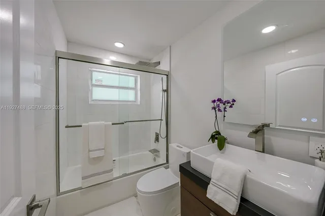 a bathroom with a granite countertop sink a toilet and shower