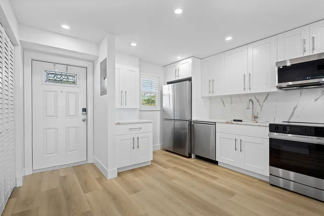 a kitchen with white cabinets stainless steel appliances and sink