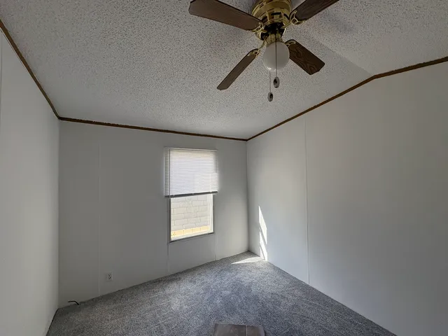 an empty room with windows and ceiling fan