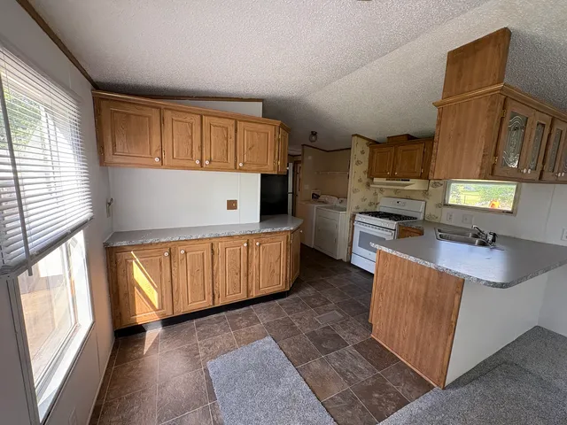 a kitchen with stainless steel appliances granite countertop a stove a sink and a refrigerator
