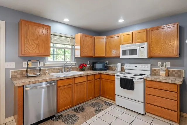a kitchen with stainless steel appliances granite countertop wooden cabinets sink and window
