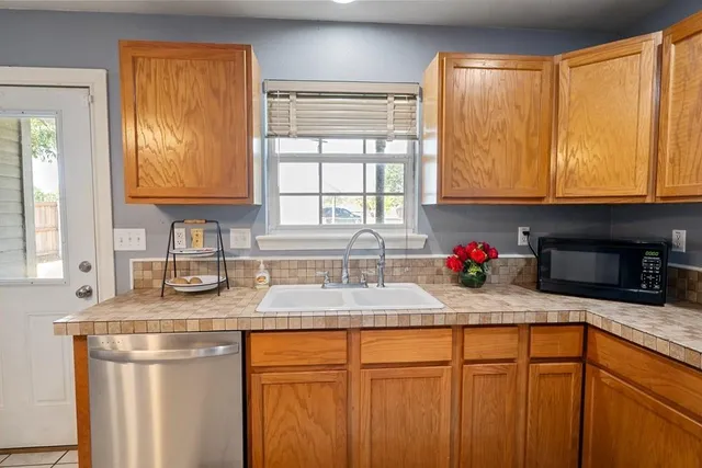 a kitchen with granite countertop stainless steel appliances a sink window and cabinets
