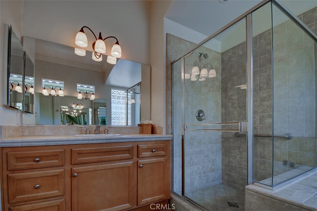 9152 Deergrass Street Corona, CA 92883 - Photo 22 of 32 a bathroom with a granite countertop sink a mirror and a shower