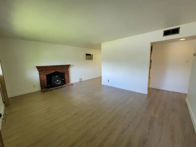 an empty room with a fireplace and wooden floor