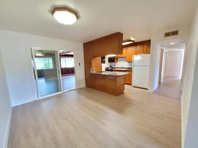 a view of a kitchen with a sink refrigerator wooden floor and a window