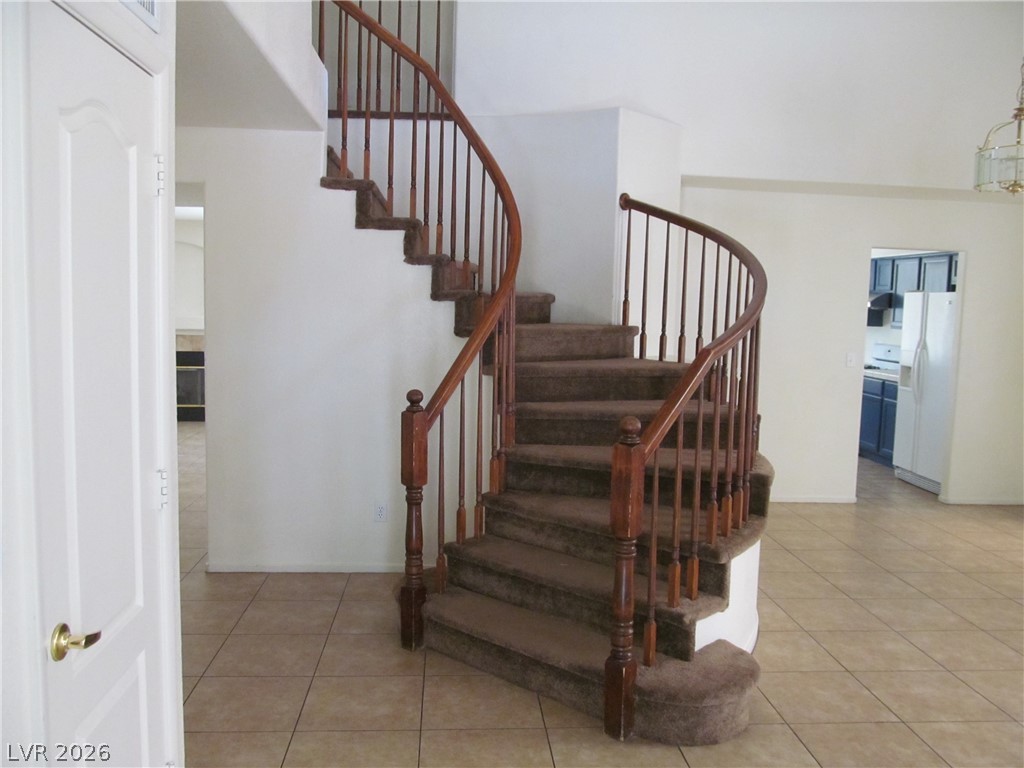 8701 Crescent Ridge Lane Las Vegas, NV 89134 - Photo 4 of 28 An elegant curved staircase with rich wooden banisters anchors this spacious entry, offering a graceful transition between floors.