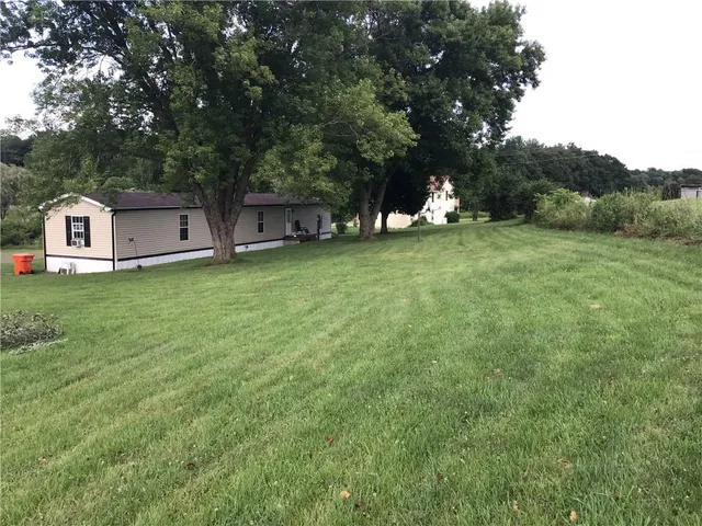 a front view of a house with a garden and trees