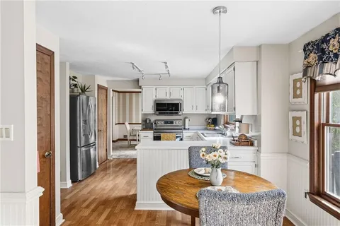 a kitchen with stainless steel appliances granite countertop a refrigerator a stove top oven a sink dishwasher and white cabinets with wooden floor