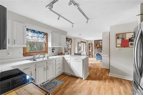 a kitchen with stainless steel appliances granite countertop a refrigerator a sink dishwasher a stove and white countertops with wooden floor