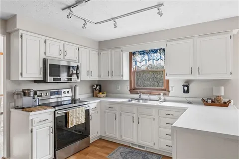 a large kitchen with stainless steel appliances granite countertop a sink and dishwasher a stove top oven with white cabinets