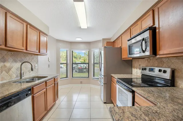 a kitchen with stainless steel appliances granite countertop a stove a sink and a microwave