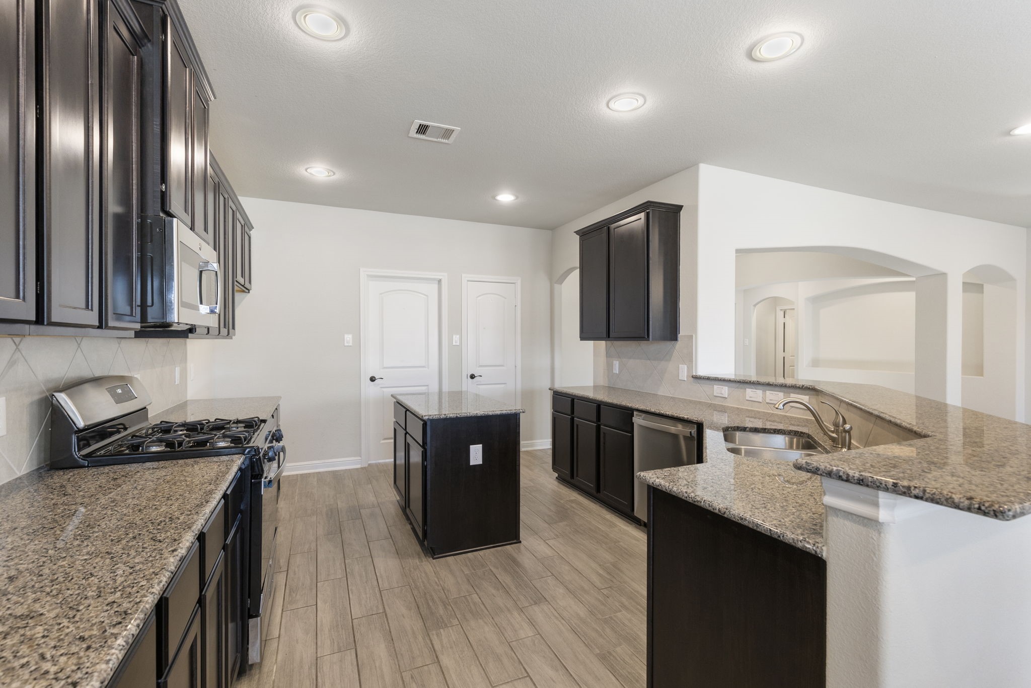 2819 Bradbury Hills Road Spring, TX 77373 - Photo 22 of 50 This modern kitchen boasts sleek dark cabinetry, polished granite countertops, and stainless steel appliances, creating an inviting space perfect for culinary adventures and gatherings.