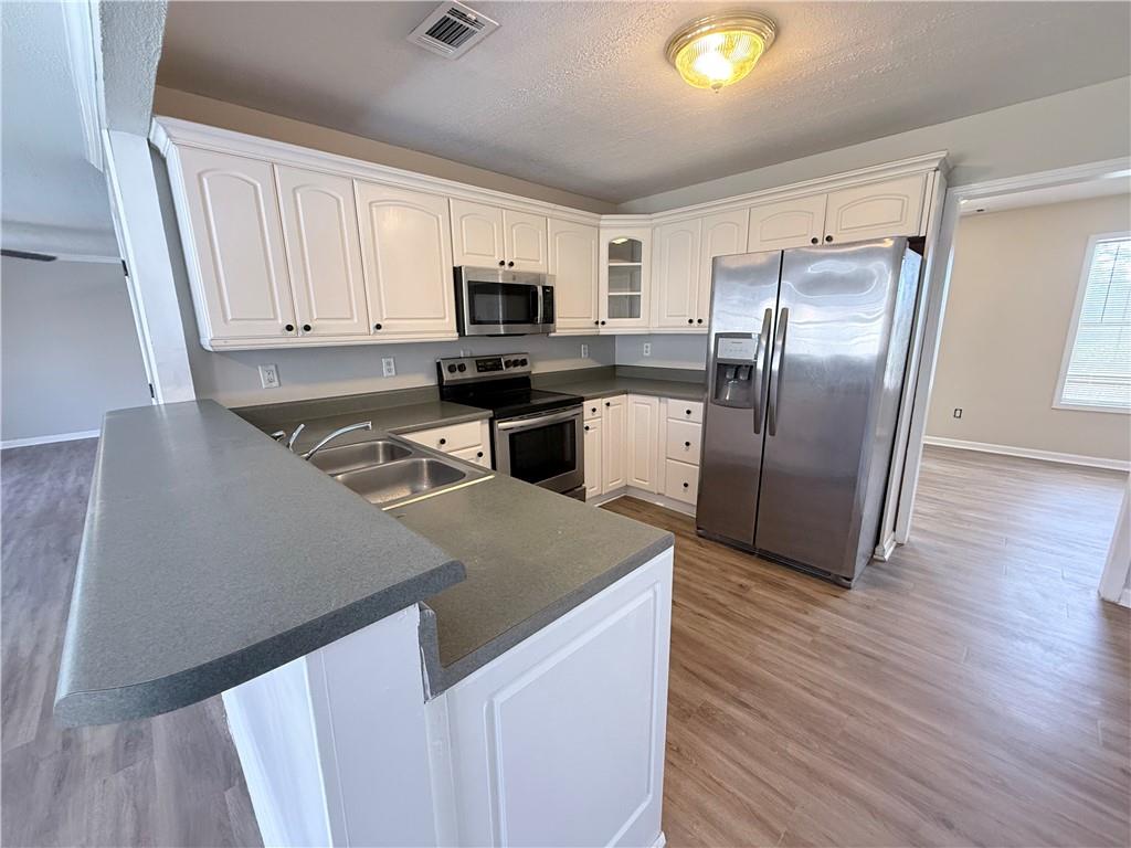 2000 Sage Court Loganville, GA 30052 - Photo 17 of 77 a kitchen with stainless steel appliances granite countertop a refrigerator a stove top oven a sink and dishwasher with wooden floor
