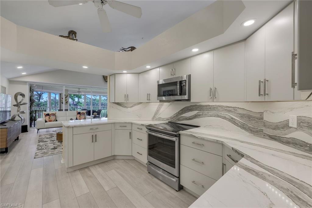a large white kitchen with stainless steel appliances granite countertop a sink and dishwasher a stove top oven with wooden floor