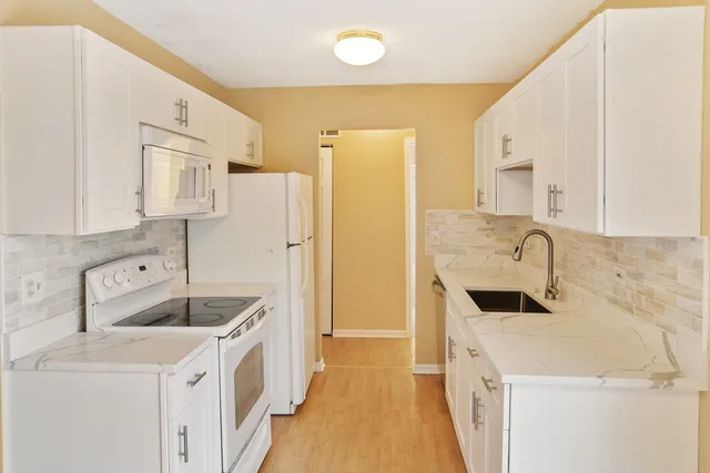 a kitchen with stainless steel appliances a stove a sink a refrigerator and a cabinets