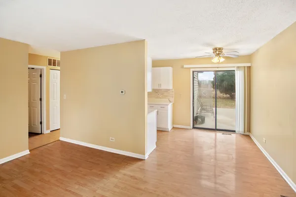a view of an empty room with wooden floor and a bathroom