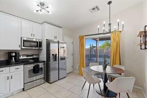 a kitchen with stainless steel appliances granite countertop a refrigerator a stove a kitchen island a dining table and chairs with wooden floor