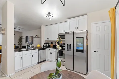a kitchen with stainless steel appliances kitchen island granite countertop a refrigerator a sink a stove and white cabinets