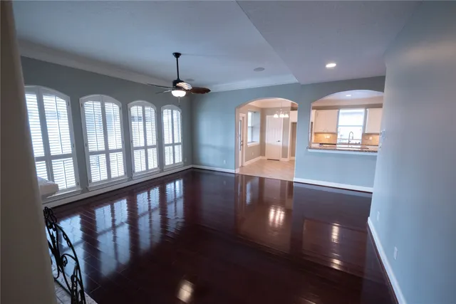 an empty room with wooden floor chandelier and windows
