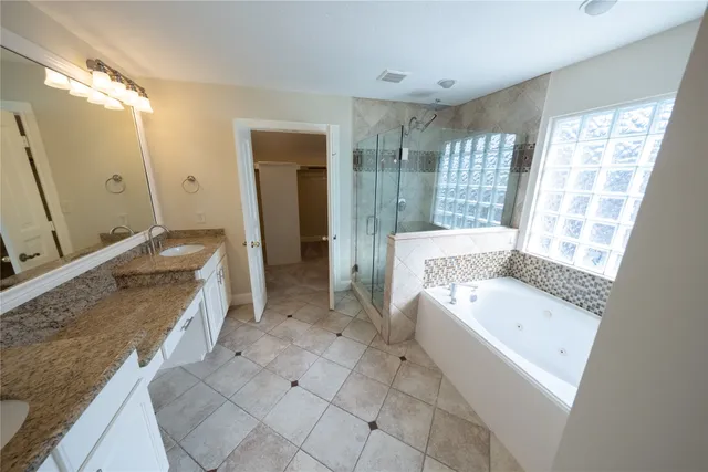 a spacious bathroom with a granite countertop tub sink a mirror and a bathtub