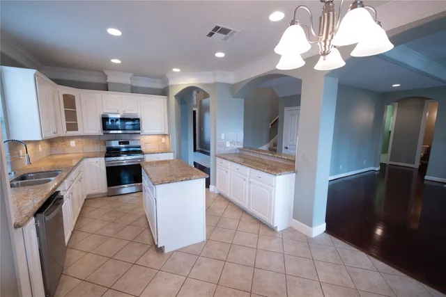 a large kitchen with stainless steel appliances granite countertop a refrigerator a stove and a sink