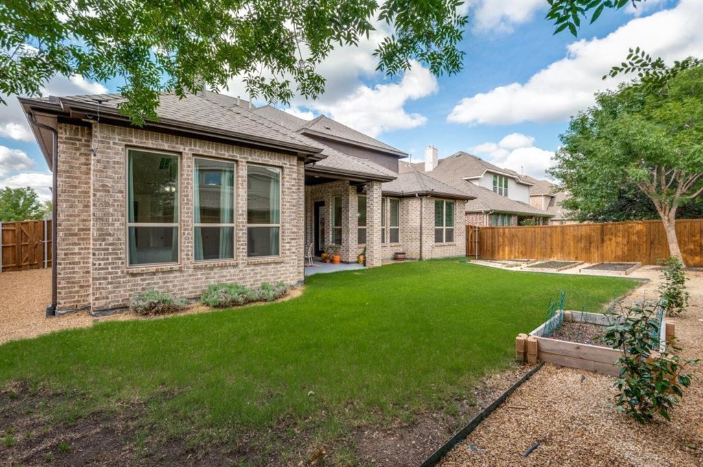 14215 Raspberry Lane Frisco, TX 75035 - Photo 23 of 30 Expansive backyard featuring a manicured lawn, a gravel border, raised garden beds, and a wood privacy fence