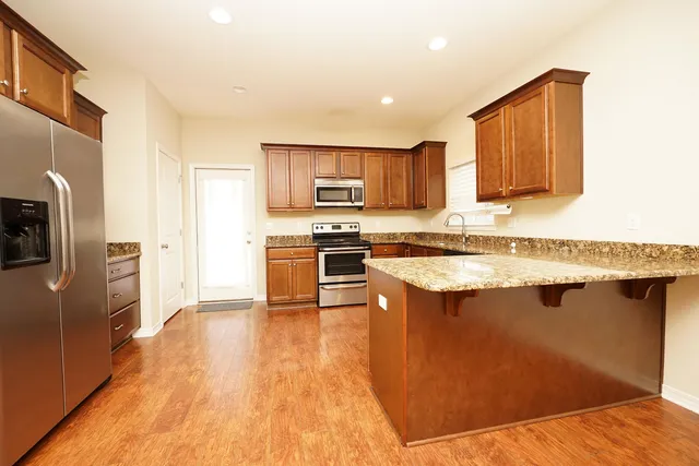 a kitchen with stainless steel appliances granite countertop a refrigerator a stove top oven a sink and dishwasher