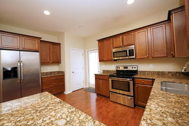 a kitchen with granite countertop wooden cabinets a stainless steel appliances and a center island