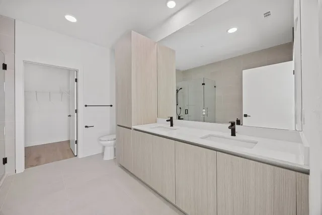 a bathroom with a double vanity sink and mirror with toilet