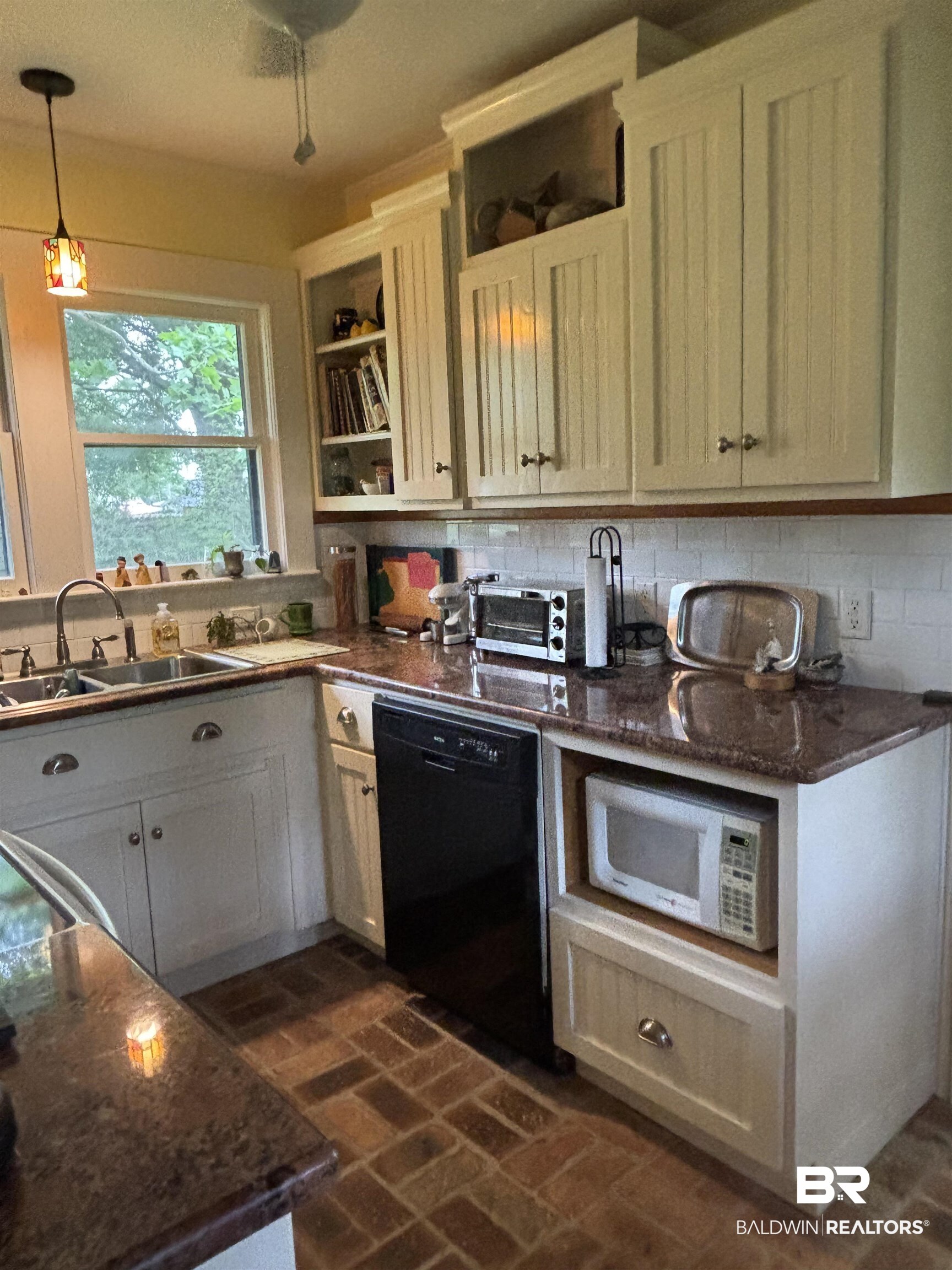 216 West Orange Avenue Foley, AL 36535 - Photo 28 of 37 Kitchen with dishwasher, a sink, white microwave, open shelves, and brick floors