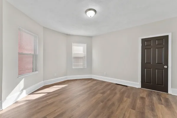 a view of empty room with wooden floor